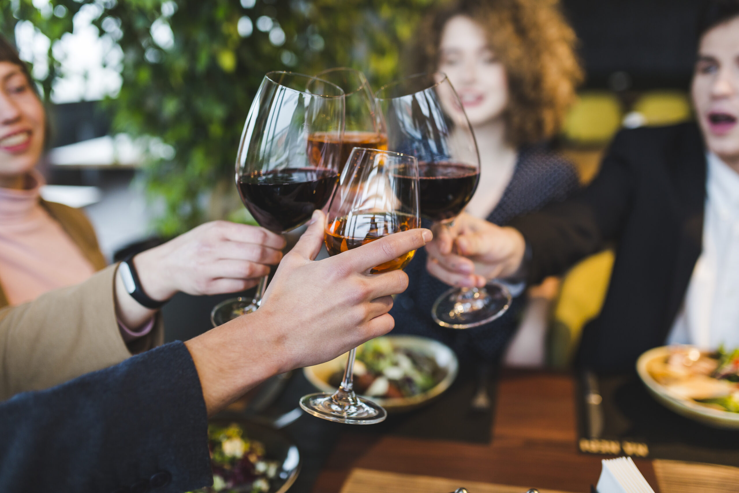 Group of friends toasting with wine glasses at a restaurant.