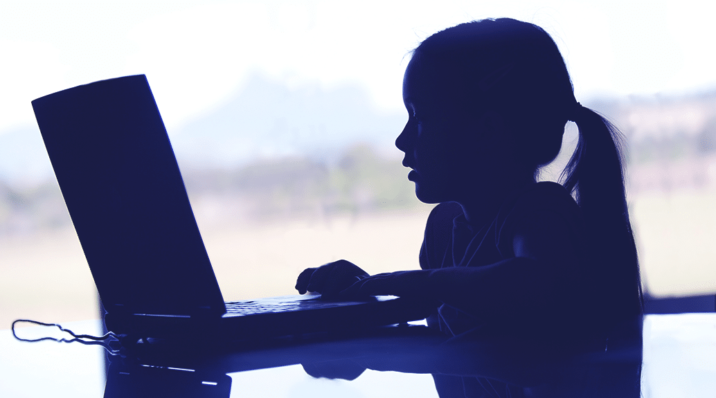 Child using laptop in silhouette