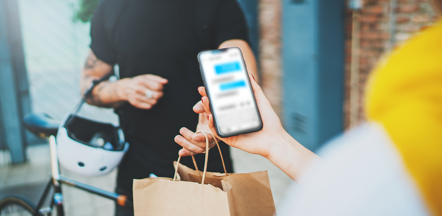 Person receiving a food delivery while checking details on a smartphone.