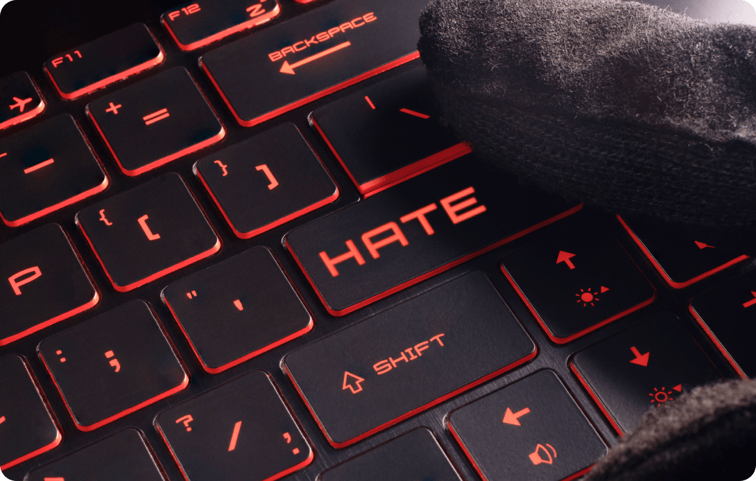 Close-up of a backlit keyboard with the word 'HATE' replacing one of the keys, illuminated in red.