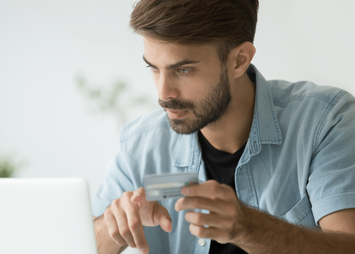 Man using a credit card to make an online purchase on his laptop.