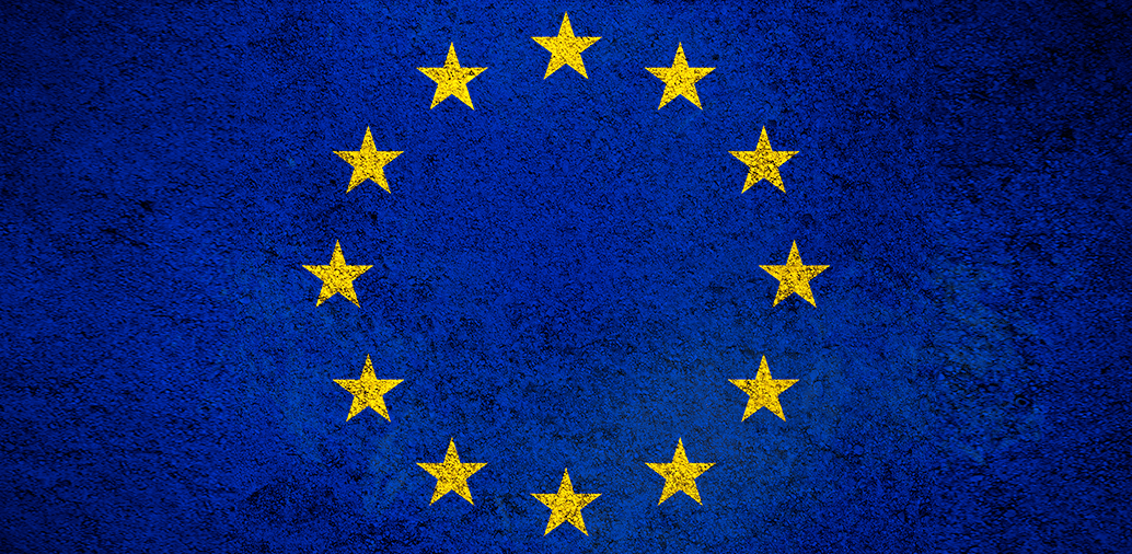 European Union flag with twelve yellow stars in a circle on a blue textured background.